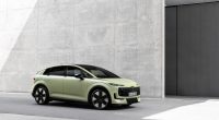 Audi A2 e-tron açık yeşil gövdesiyle beton bir binanın önünde