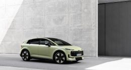Audi A2 e-tron açık yeşil gövdesiyle beton bir binanın önünde