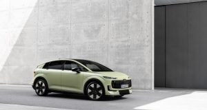 Audi A2 e-tron açık yeşil gövdesiyle beton bir binanın önünde