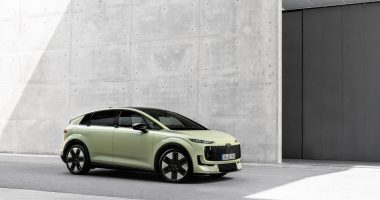 Audi A2 e-tron açık yeşil gövdesiyle beton bir binanın önünde
