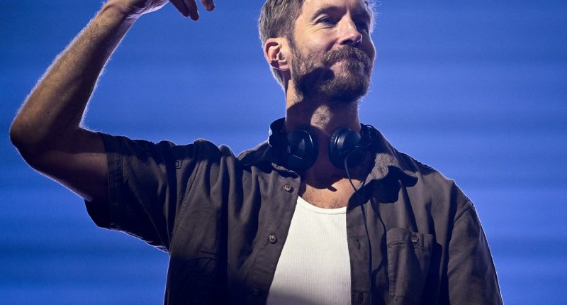 Kulaklığı boynunda, elini havaya kaldıran Calvin Harris