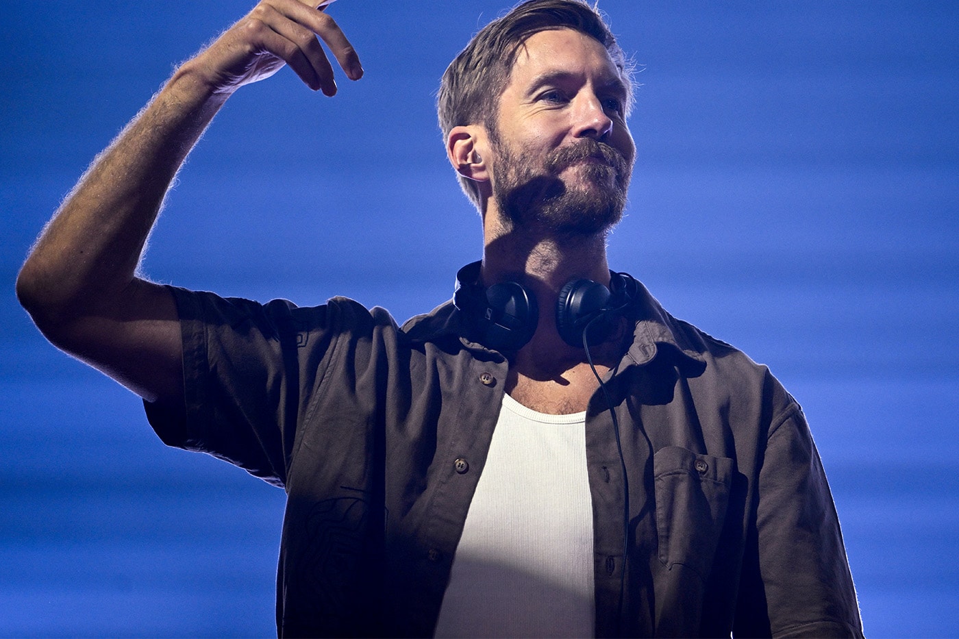Kulaklığı boynunda, elini havaya kaldıran Calvin Harris