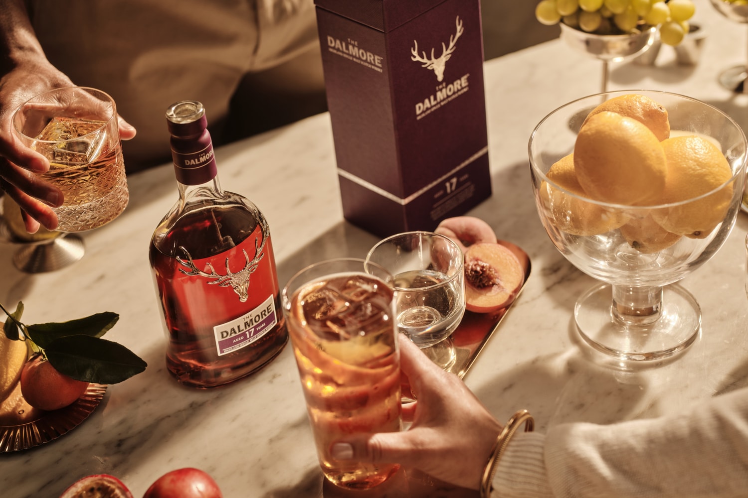 Meyveler ve bardaklar arasında Dalmore 17 şişesi