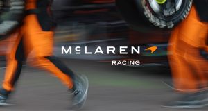 Pit alanında McLaren Racing yazısı ve turuncu tulumlu ekip