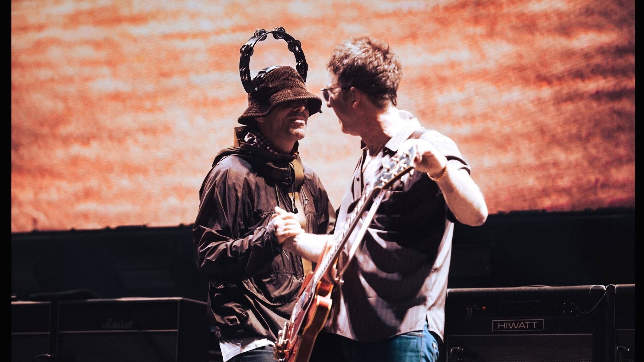 Bucket şapkası ve başındaki tefiyle Liam Gallagher sahnede gülüyor