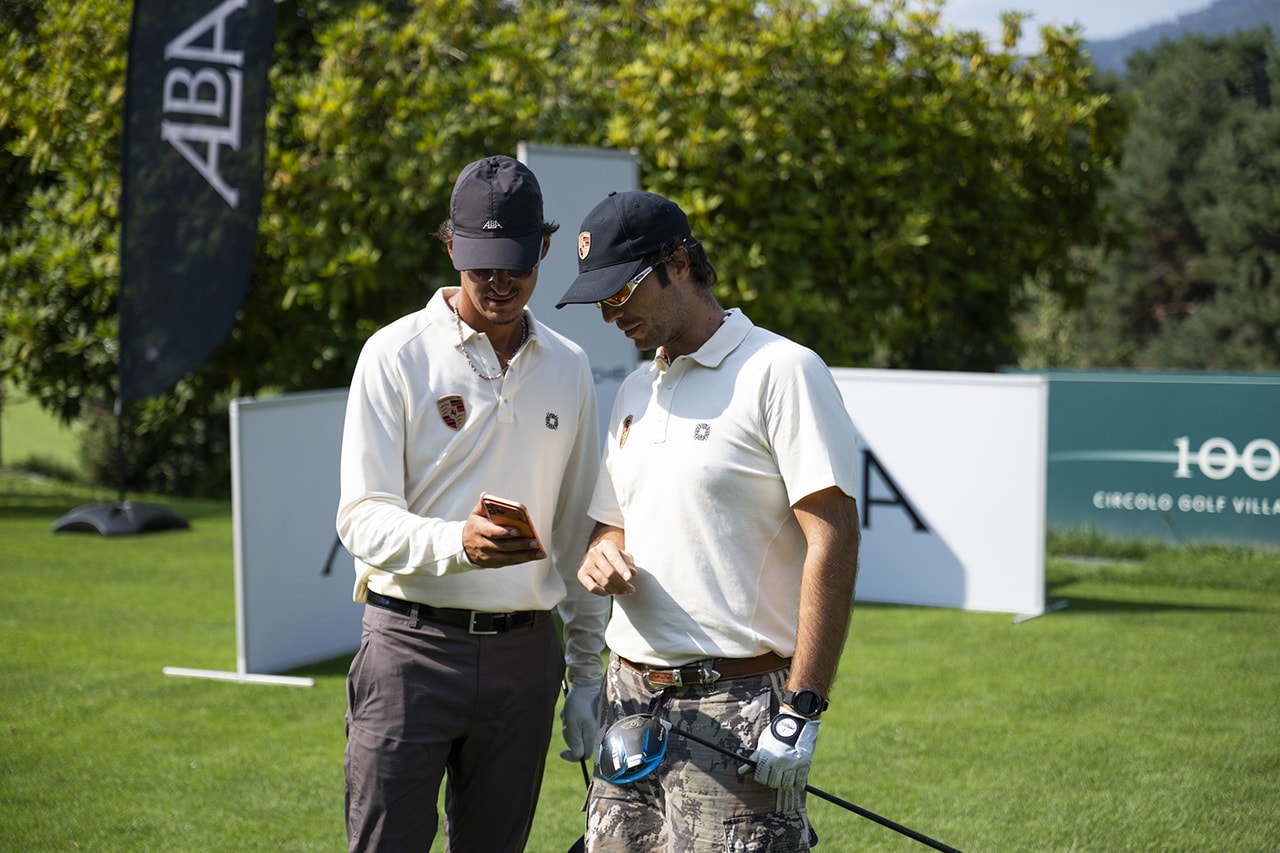 Alba golf turnuvasında beyaz polo tişörtlü iki oyuncu
