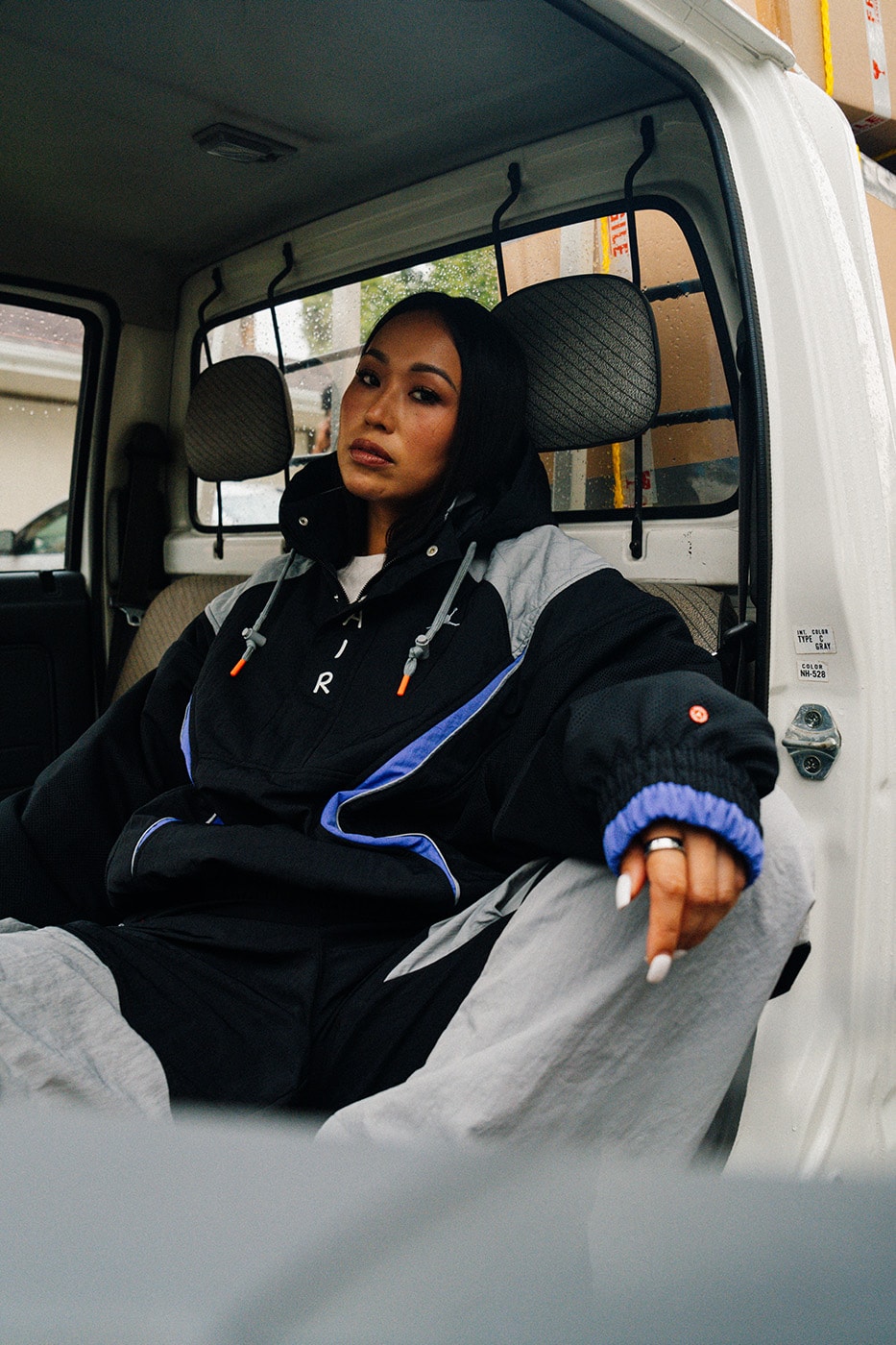 Kamyonette oturan model, anorak ve gri pantolon