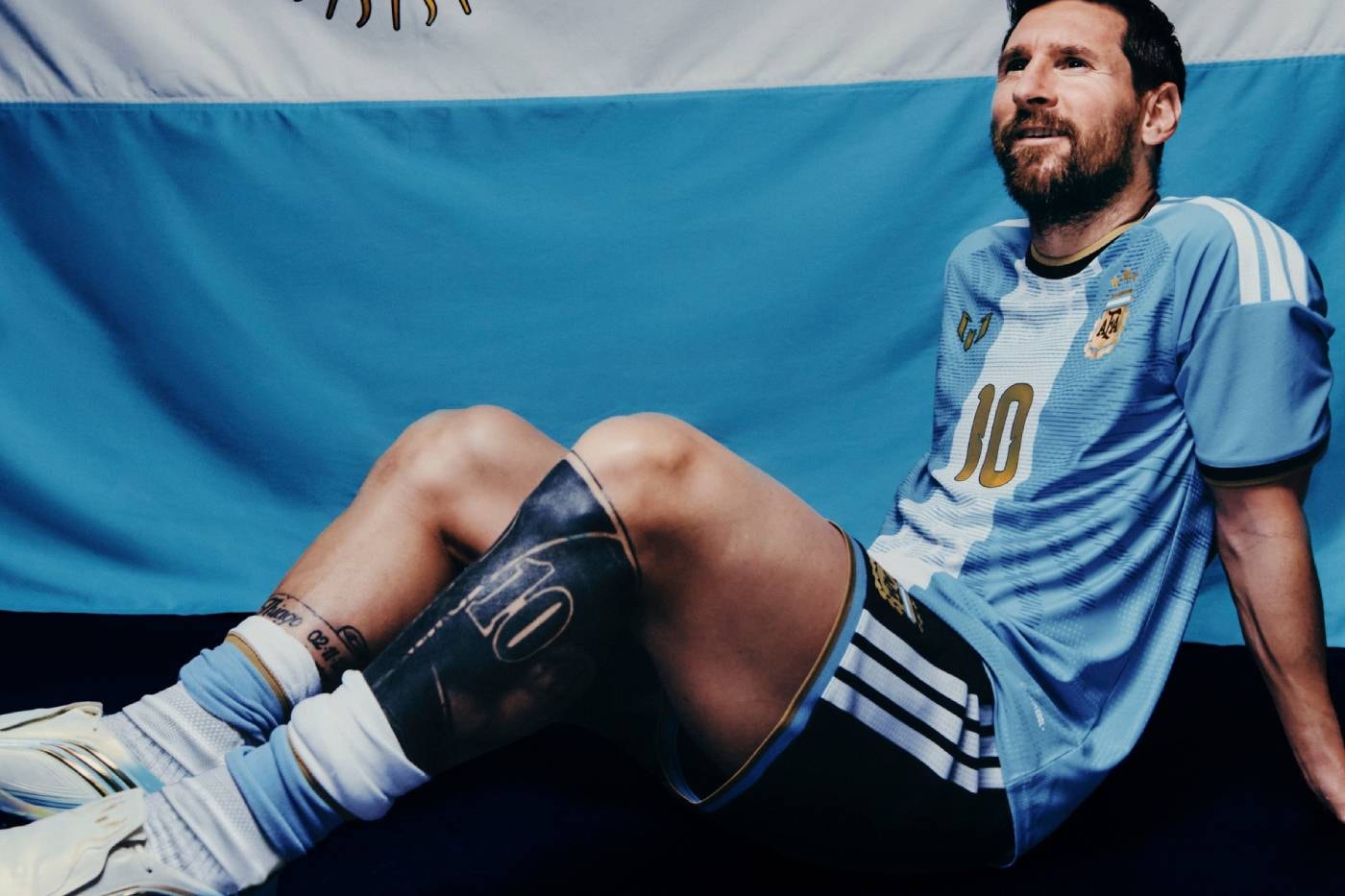 Arjantin bayrağı önünde yerde oturan Messi, sırtında veda forması