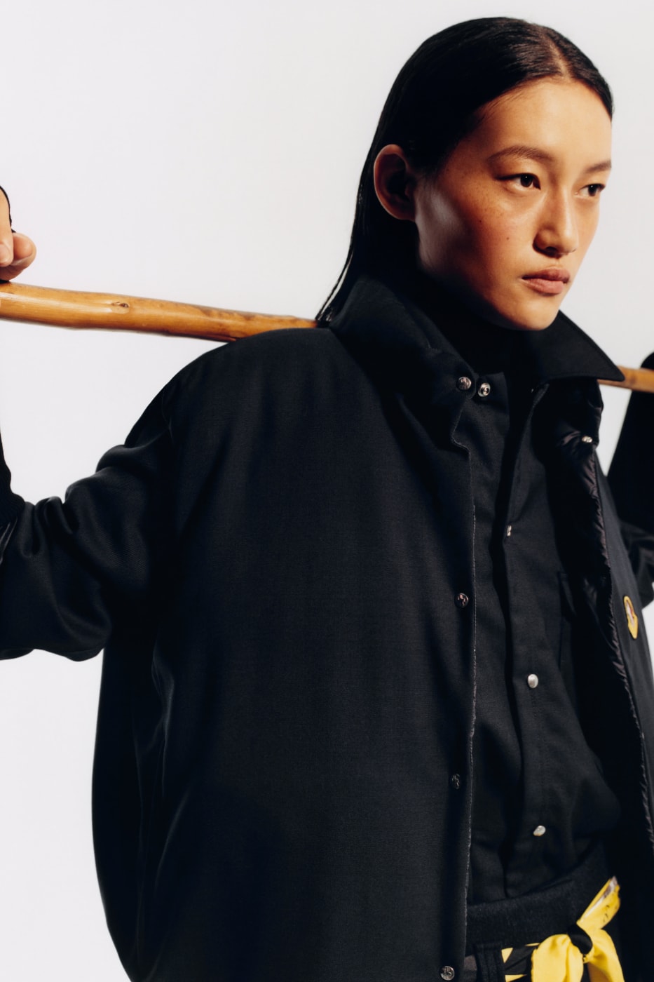 Moncler Re/Icons 2026 siyah ceket ve omuzda ahşap sopa