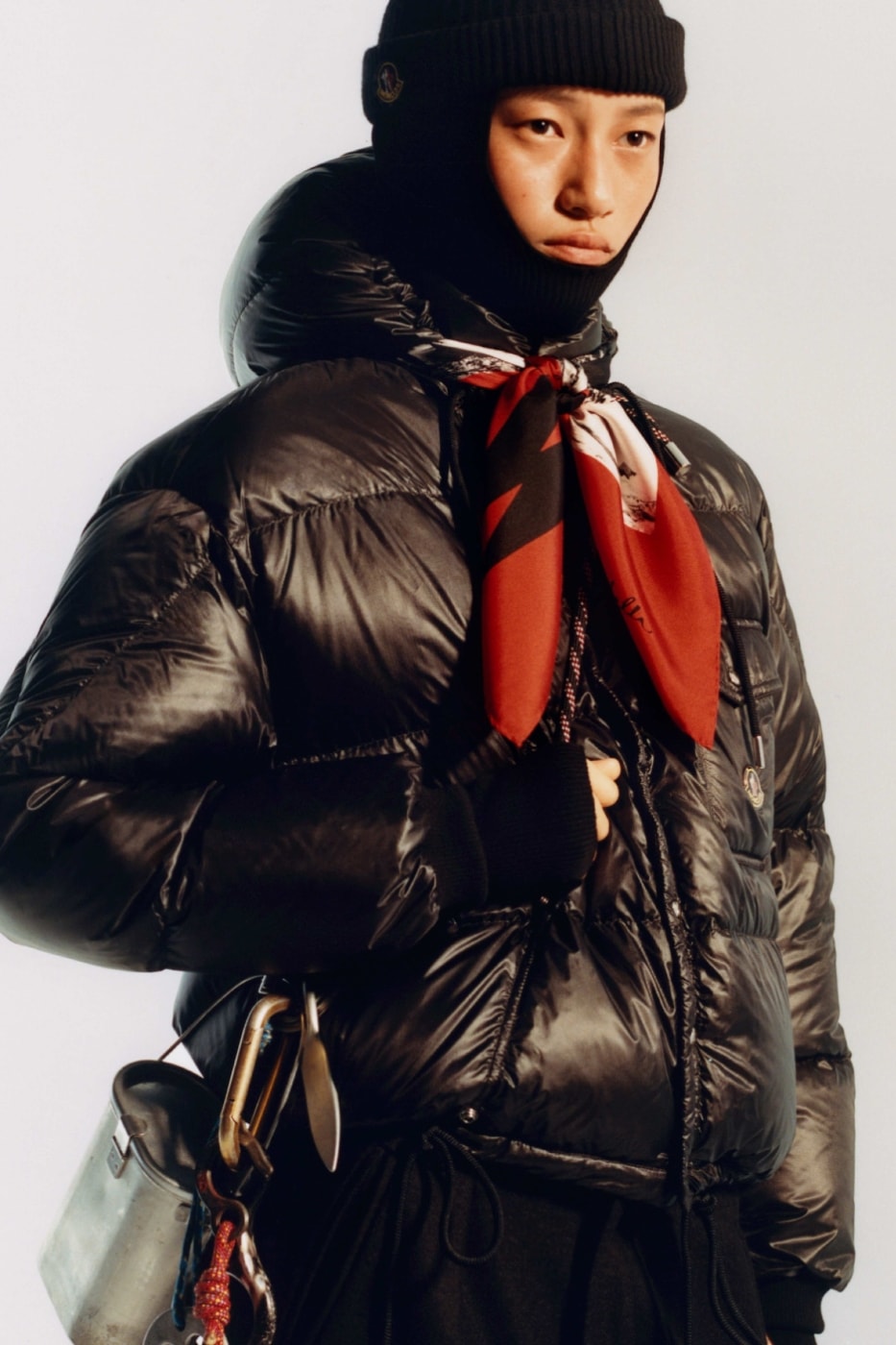 Moncler Re/Icons 2026 siyah parlak puf mont ve kırmızı fular