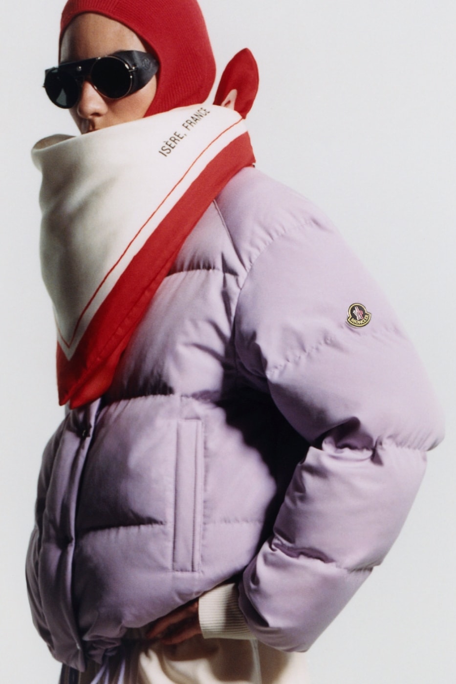Moncler Re/Icons 2026 lila puf mont, güneş gözlüğü ve kırmızı-beyaz atkı