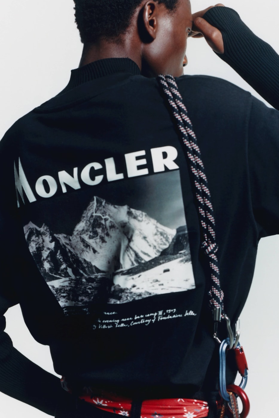 Sırtında Moncler logosu ve dağ fotoğrafı olan siyah üst
