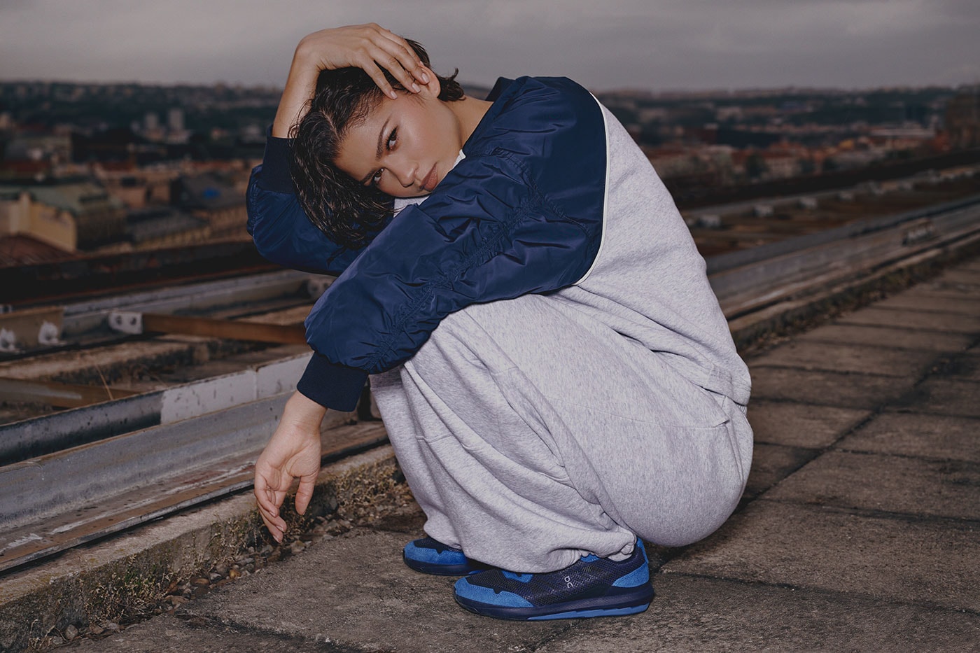 Lacivert sweatshirt ve gri eşofmanla çömelmiş poz